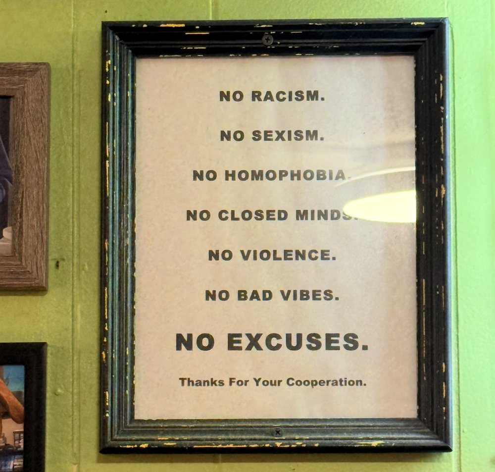 A framed sign reading: No racism. No sexism. No homophobia. No closed minds. No violence. No bad vibes. No excuses.